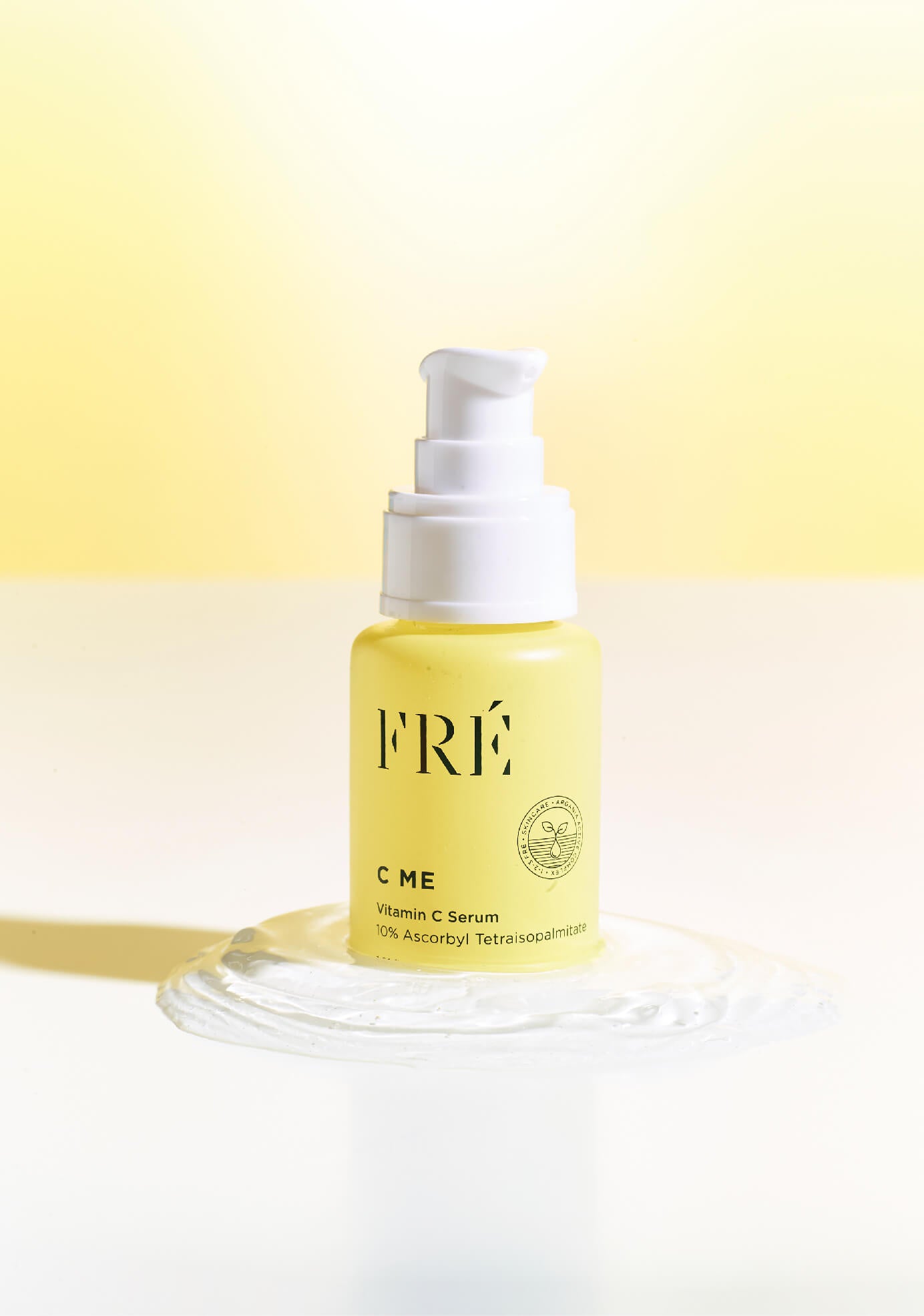 C ME - Vitamin C Serum by FRÉ - on a gel like surface with yellow background